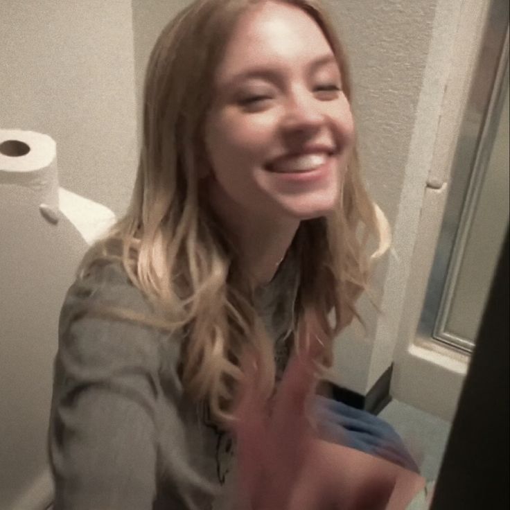 a woman is taking a selfie in the bathroom with toilet paper on the wall