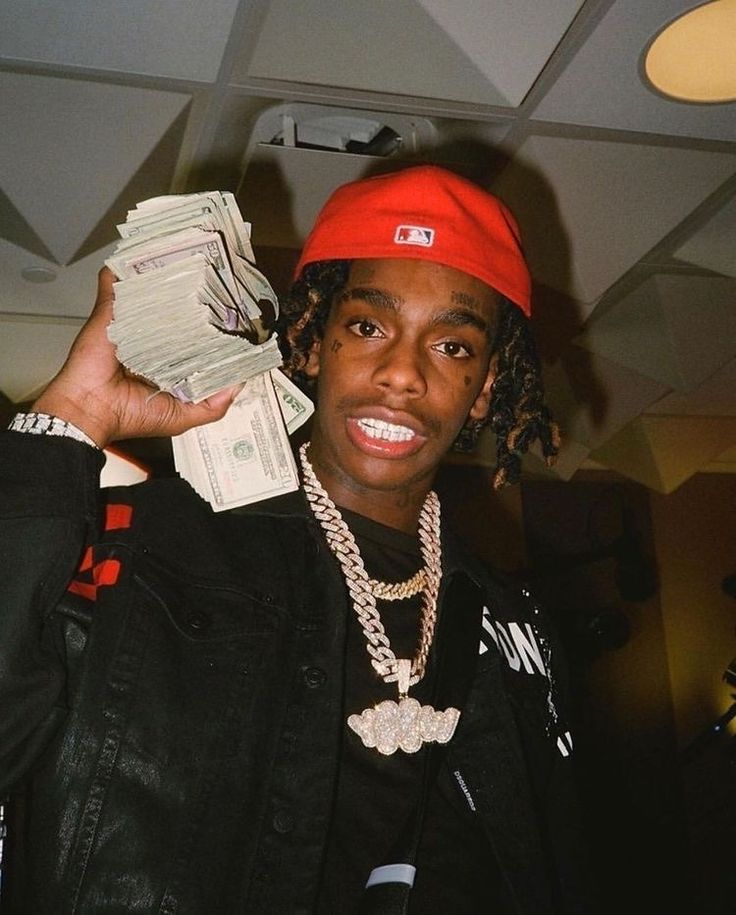 a young man wearing a red beanie and holding up stacks of money in his hand