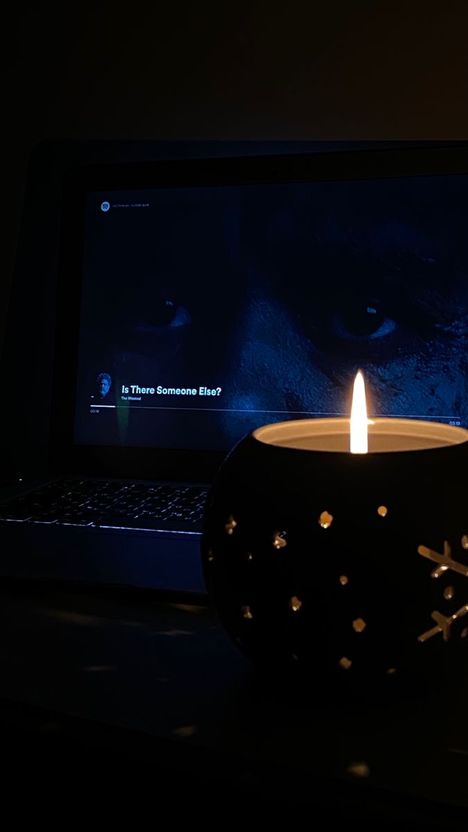 a lit candle sitting in front of a laptop on a desk with the image of a snowflake