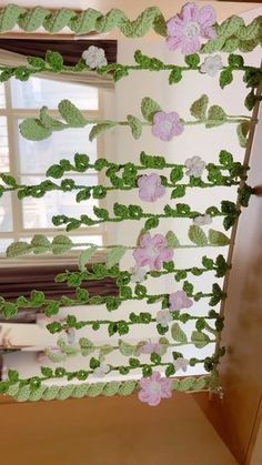 the window is decorated with green and pink paper flowers on it's side, along with greenery