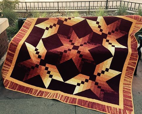 a large quilt is hanging on a bench