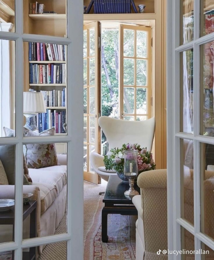 a living room filled with furniture and bookshelves next to a doorway that leads to a sitting area