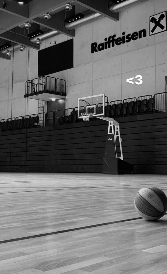 a basketball is sitting on the court in an indoor gym with stairs and bleachers