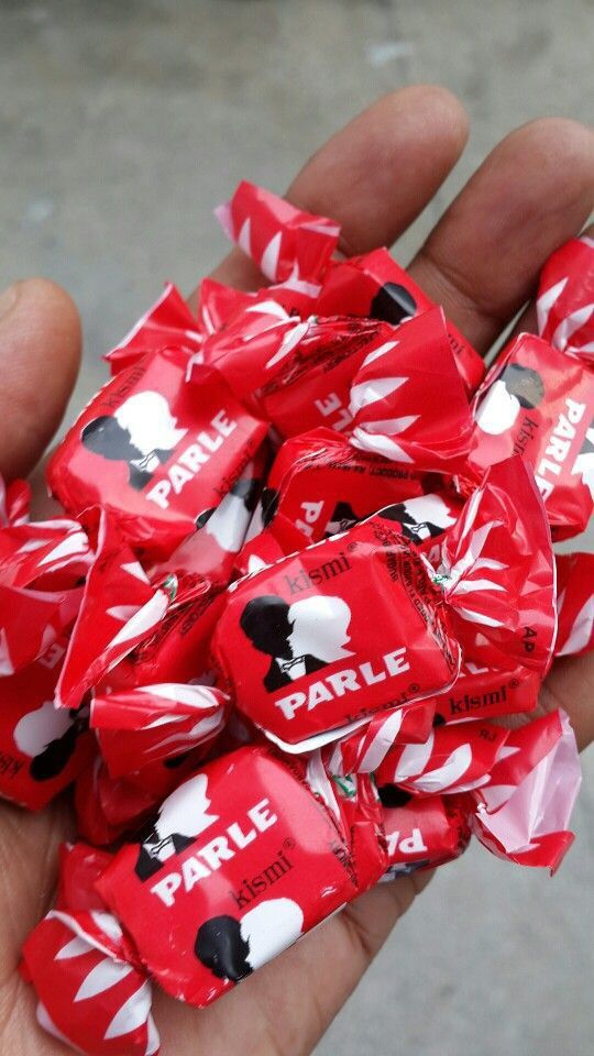 a hand holding a bunch of red and white candy wrappers with mickey mouses on them