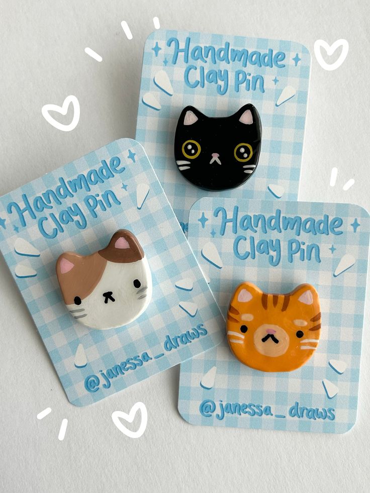 two handmade clay pin badges with cats and kittens on them, sitting next to each other