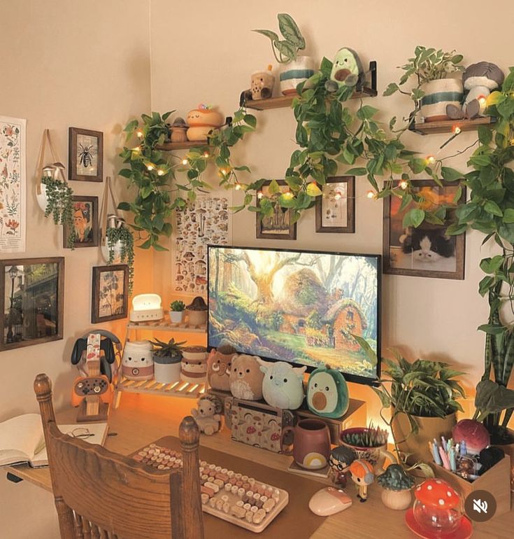 a computer desk with plants and pictures on the wall