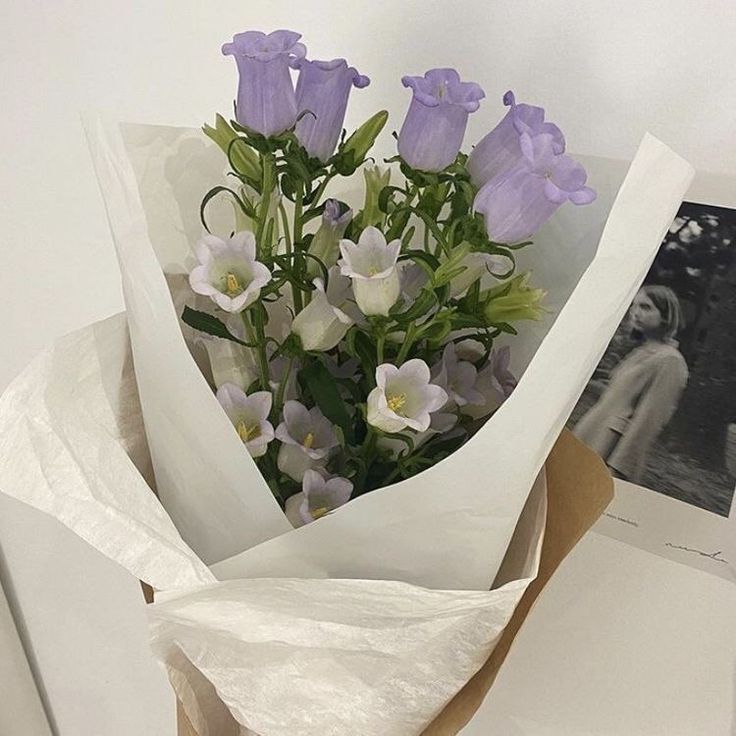 a bouquet of purple and white flowers sitting on top of a piece of parchment paper