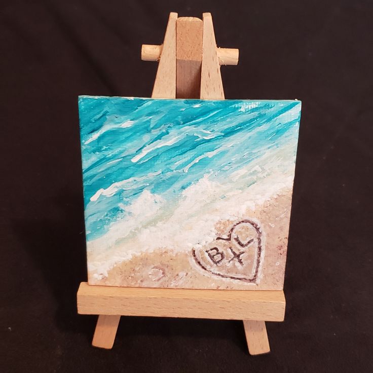 a small easel with a heart drawn in the sand