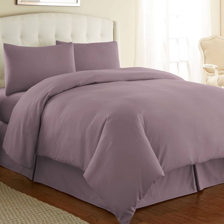 a bed with purple sheets and pillows in a room