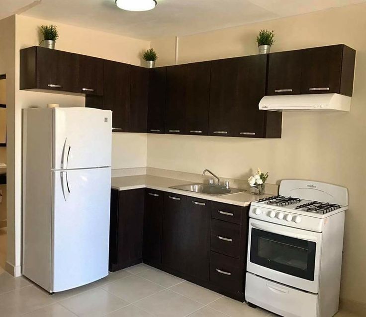 an empty kitchen with white appliances and brown cupboards on the walls, along with dark wood cabinets