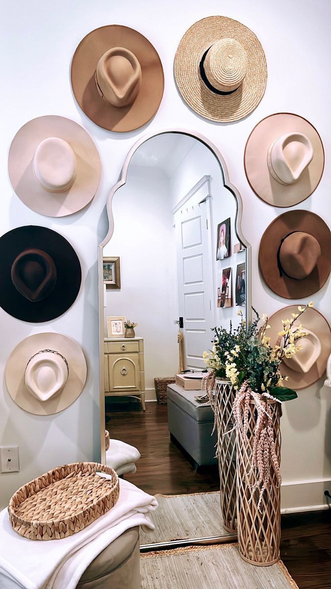 a room with hats on the wall and a vase full of flowers in front of it