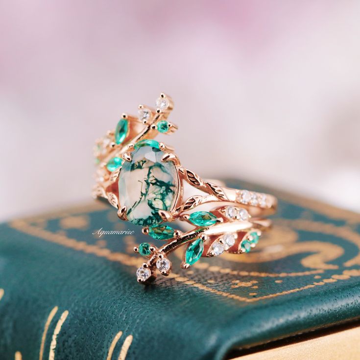 a close up of a ring on top of a book with green and white stones