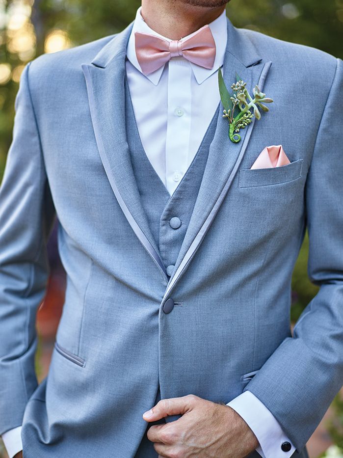 a man in a gray suit with a pink bow tie and boutonniere