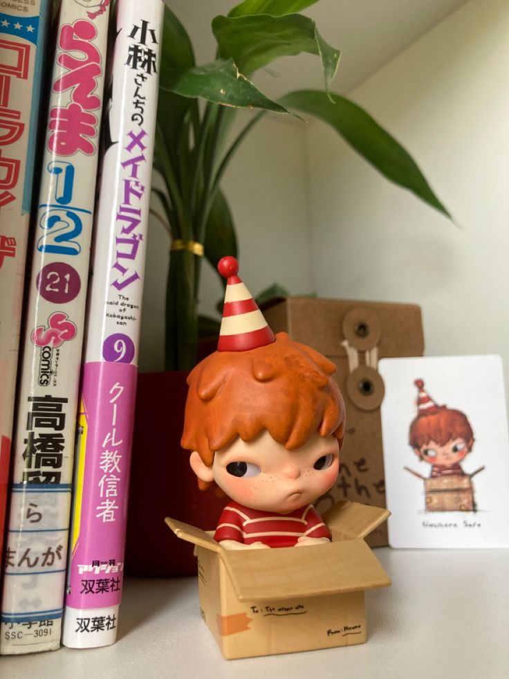 a small figurine is sitting in a box on a shelf next to books