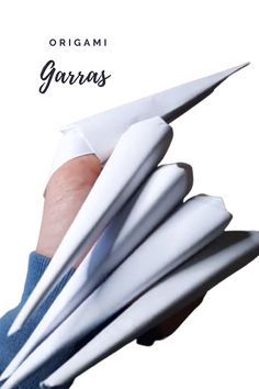 an image of a person's hand holding several folded paper objects with the words origami garras on it