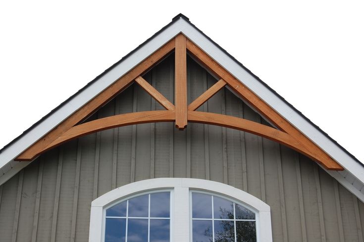 an arched window on the side of a gray building with white trim and wood accents