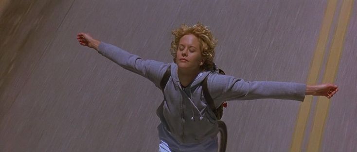 a woman is skateboarding down the street in the rain with her arms spread out