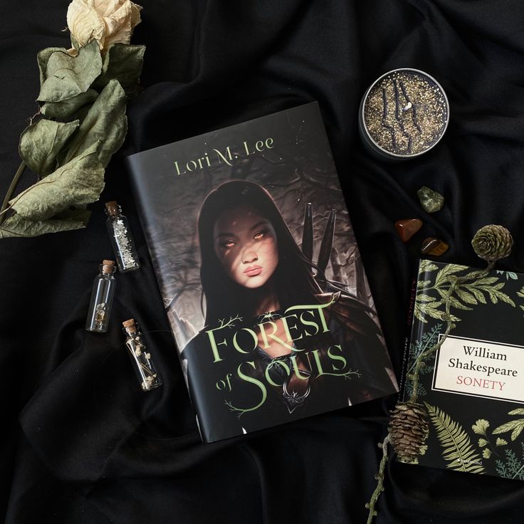 the book forest of sons by lori v lee is laying on a black cloth next to some other items