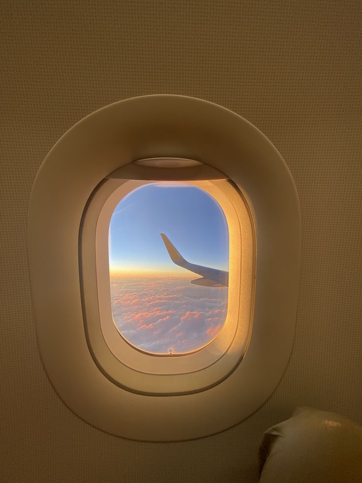 an airplane window with the view of clouds and sky from it's seat area