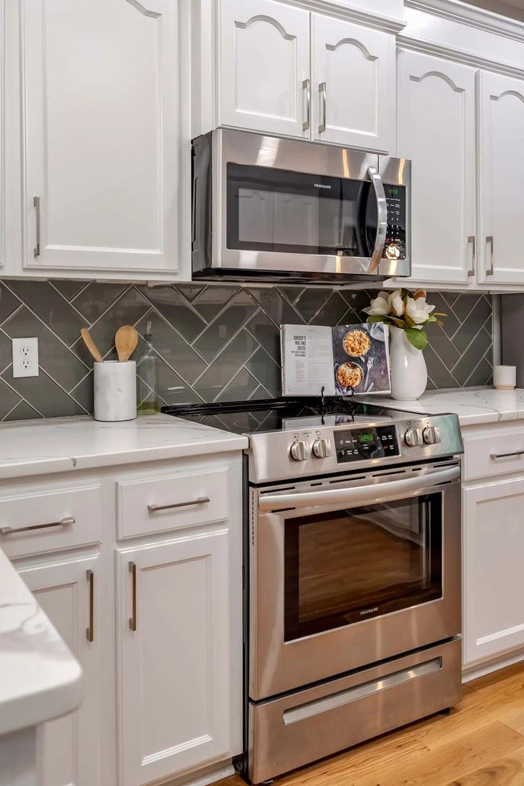 a kitchen with white cabinets and stainless steel stove top oven, microwave, and dishwasher