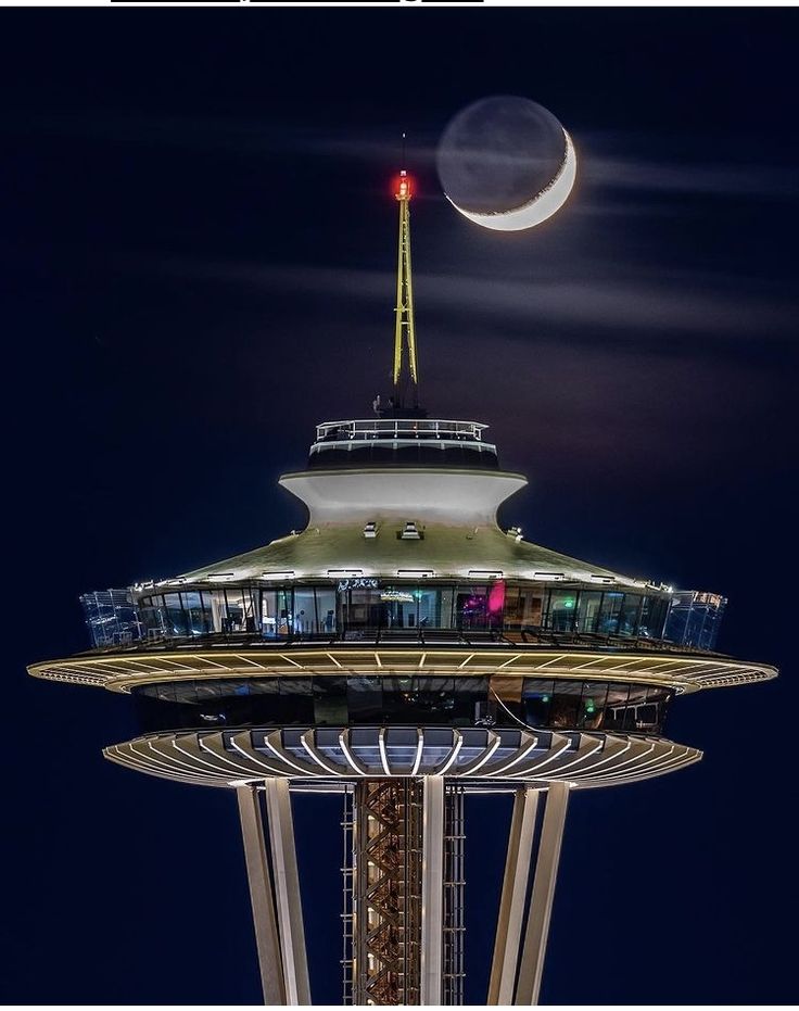 the moon is setting over the space needle in seattle, wa at night as seen from below