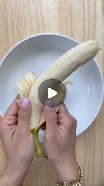 a person holding a banana in front of a white bowl