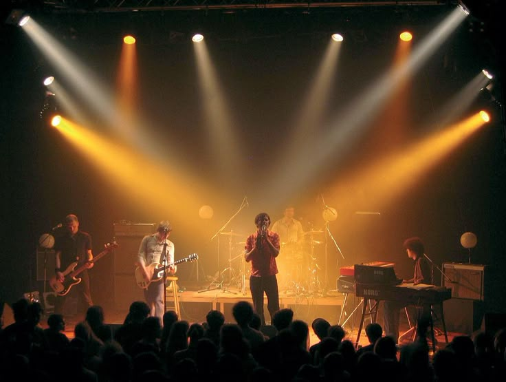 a group of people standing on top of a stage with lights coming from behind them