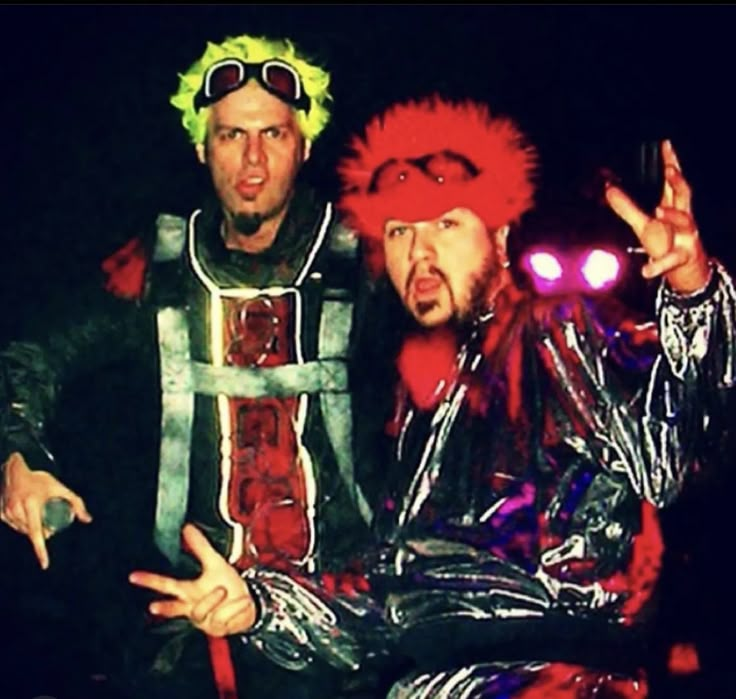 two men dressed in costumes posing for the camera with their hands up and one pointing at something