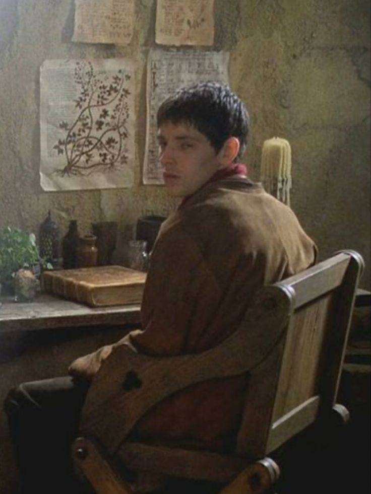 a young man sitting in a chair next to a window