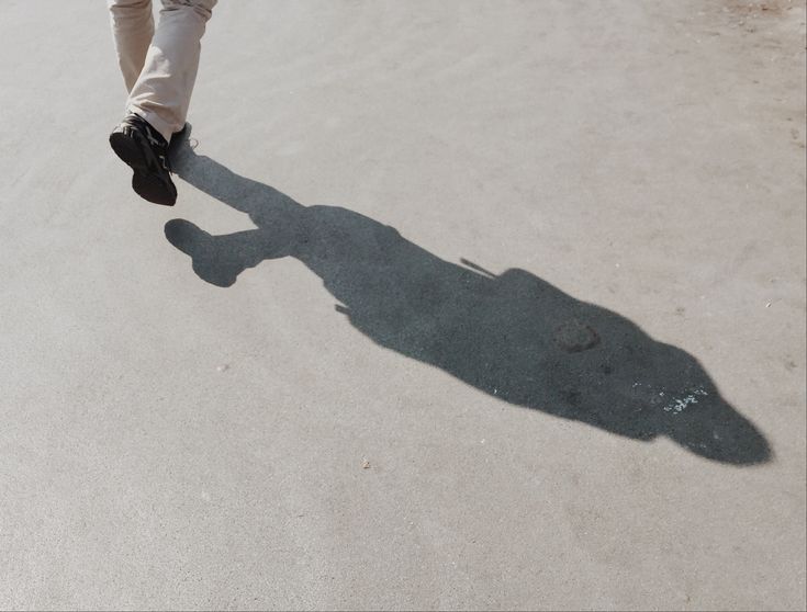 the shadow of a person's feet and shoes as they walk