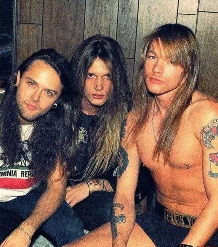 three shirtless men sitting next to each other in a room with wood paneling