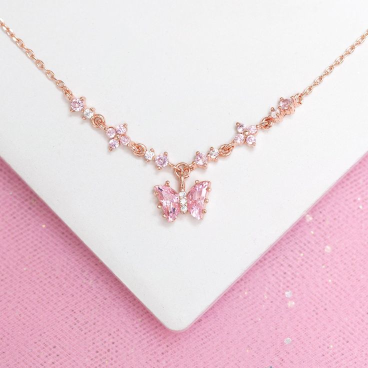 How adorable! The Flutter Love Necklace features an eye-catching baby pink butterfly in between a chain of enchanting CZ flowers. This piece radiates lustrous pink shimmers that are sure to amaze. You'll want to grab this one before it's too late! 18k gold, 18k rose gold or rhodium plated over brass with a protective coating Cubic zirconia stones 15" + 2" extension, 7mm pendant drop Shop our entire In the Garden Collection here Pink Wedding Necklace, Aesthetic Pink Accessories, Cute Pink Necklaces, Pink Butterfly Jewelry, Pink And Silver Necklace, Cute Pink Necklace, Pink Butterfly Necklace, Pink And Gold Necklace, Cute Pink Jewelry