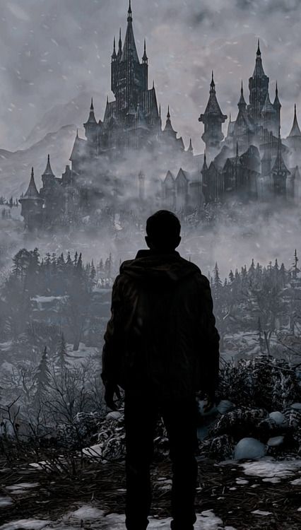 a man standing on top of a snow covered hillside looking at a castle in the distance