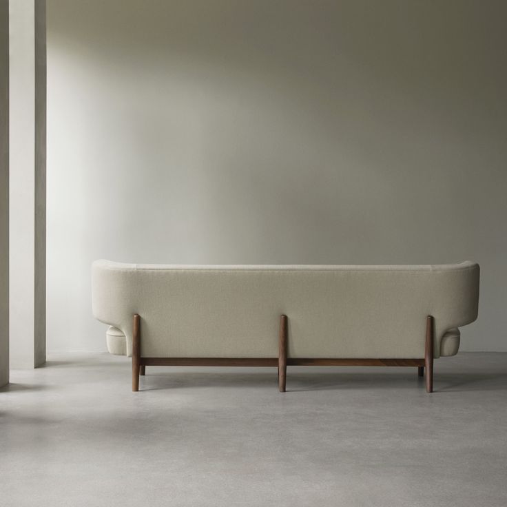 a white couch sitting on top of a cement floor next to a tall wooden pole