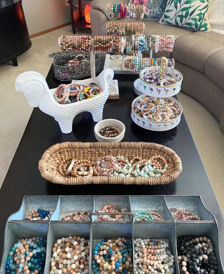 a table filled with lots of different types of beads and bracelets on display in baskets