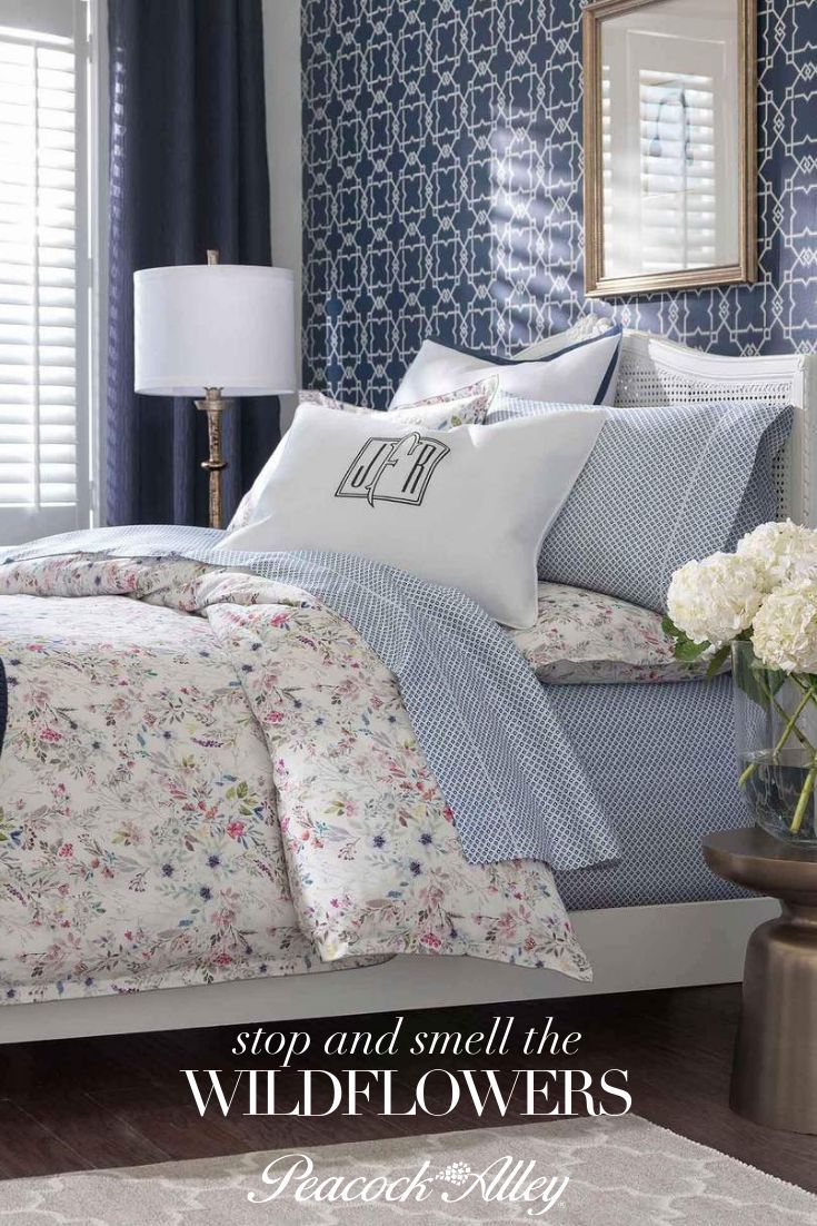 a bed in a bedroom with blue and white wallpaper, pillows and blankets on it