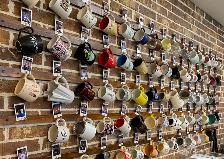 coffee cups are hanging on a brick wall