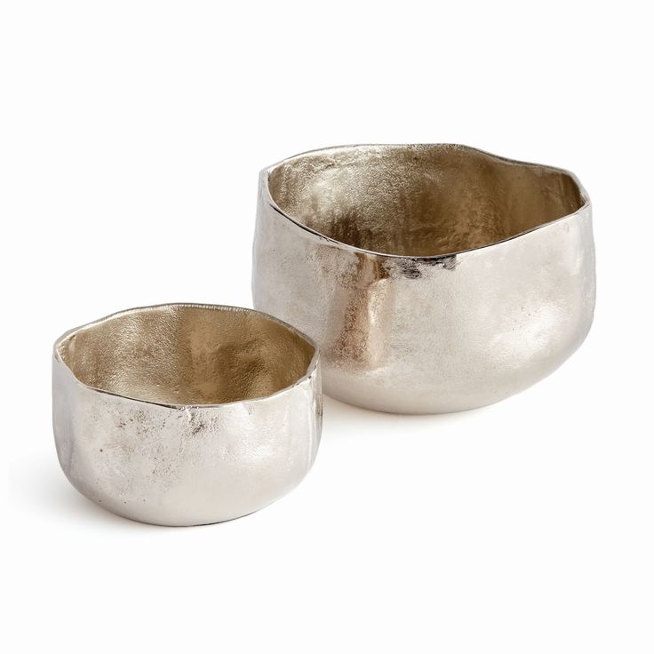 two silver bowls sitting next to each other