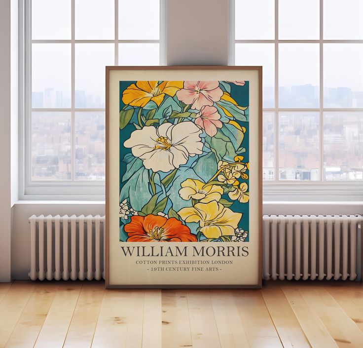 a framed poster on the floor in front of a window with an image of flowers