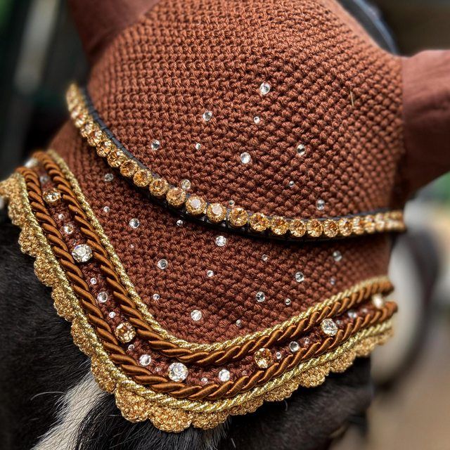 a close up of a goat wearing a hat with chains on it's back