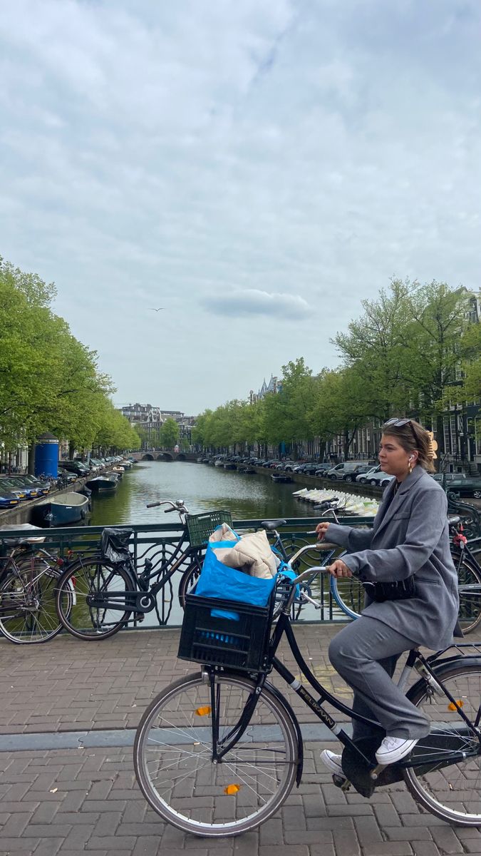 a woman riding a bike with a dog in the basket on the front and side