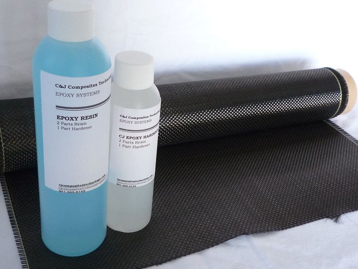 two bottles are sitting next to each other on a mat near a roll of black fabric