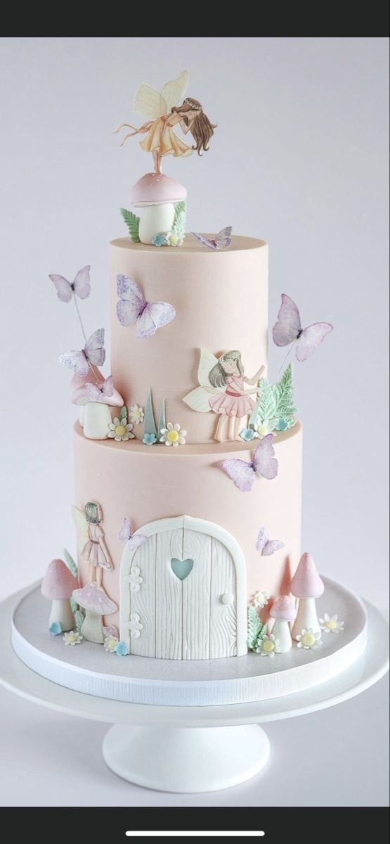 a three tiered cake with fairy figurines on top and pink frosting