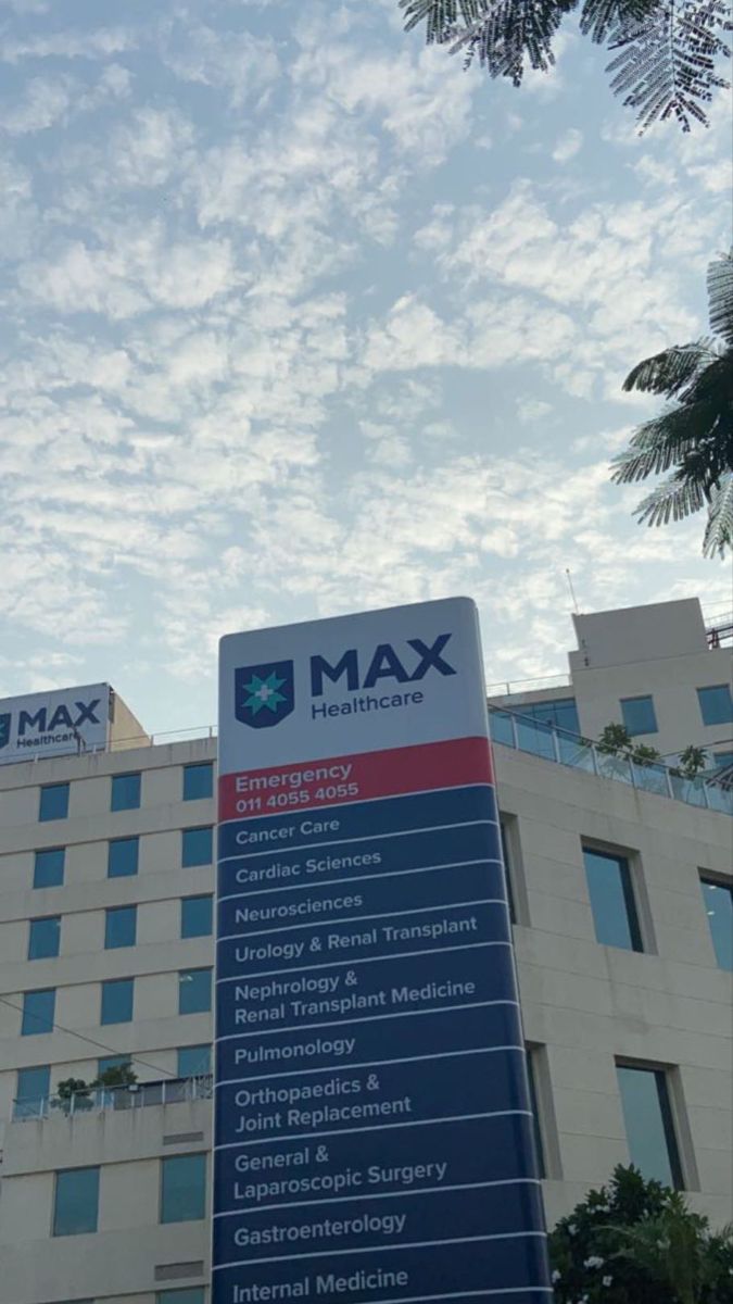 a large sign is in front of a building with many windows and palm trees around it