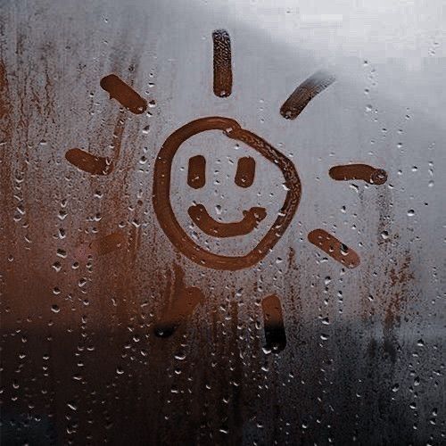 a smiley face drawn on the window with rain drops