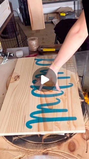 a person that is making something out of some kind of plywood board with blue lettering on it