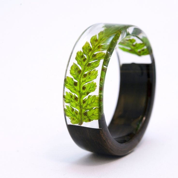 a wedding ring with green leaves painted on the inside and black wood inlays