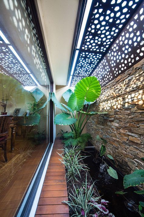 the inside of a house with lots of plants and rocks on the outside wall, along with wood flooring