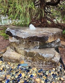 there is a rock with water coming out of it in the middle of some rocks