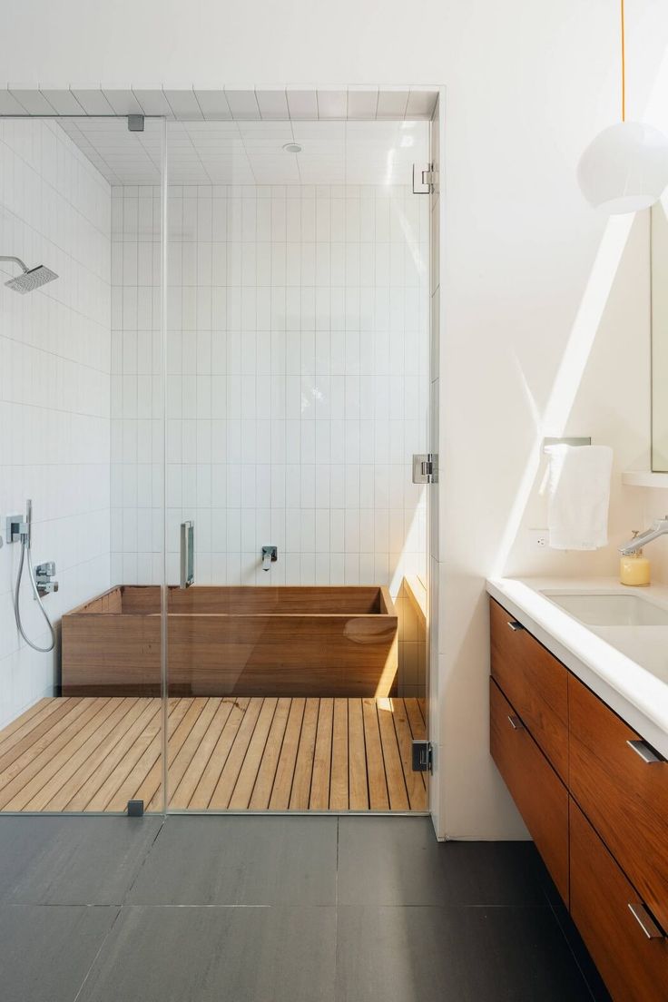 a bathroom with a wooden floor and white walls, along with a walk in shower